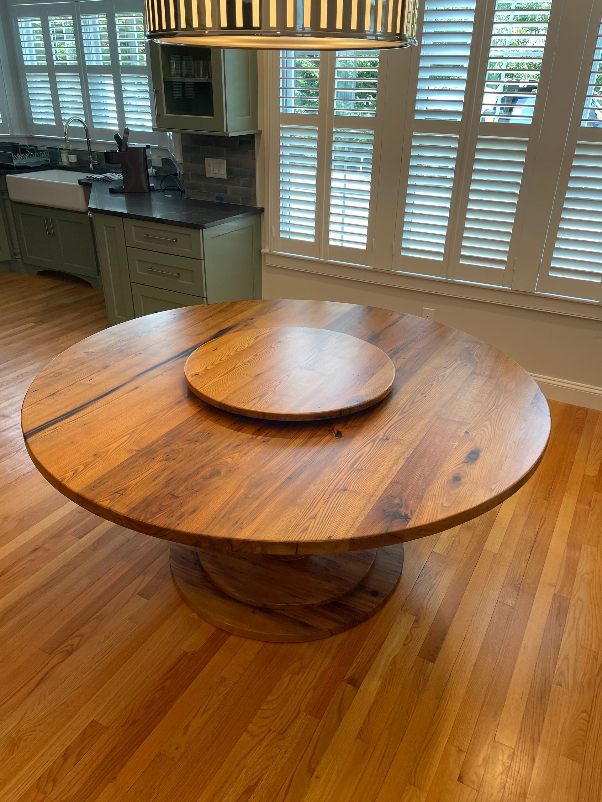 A round wooden table with a turntable in a kitchen.