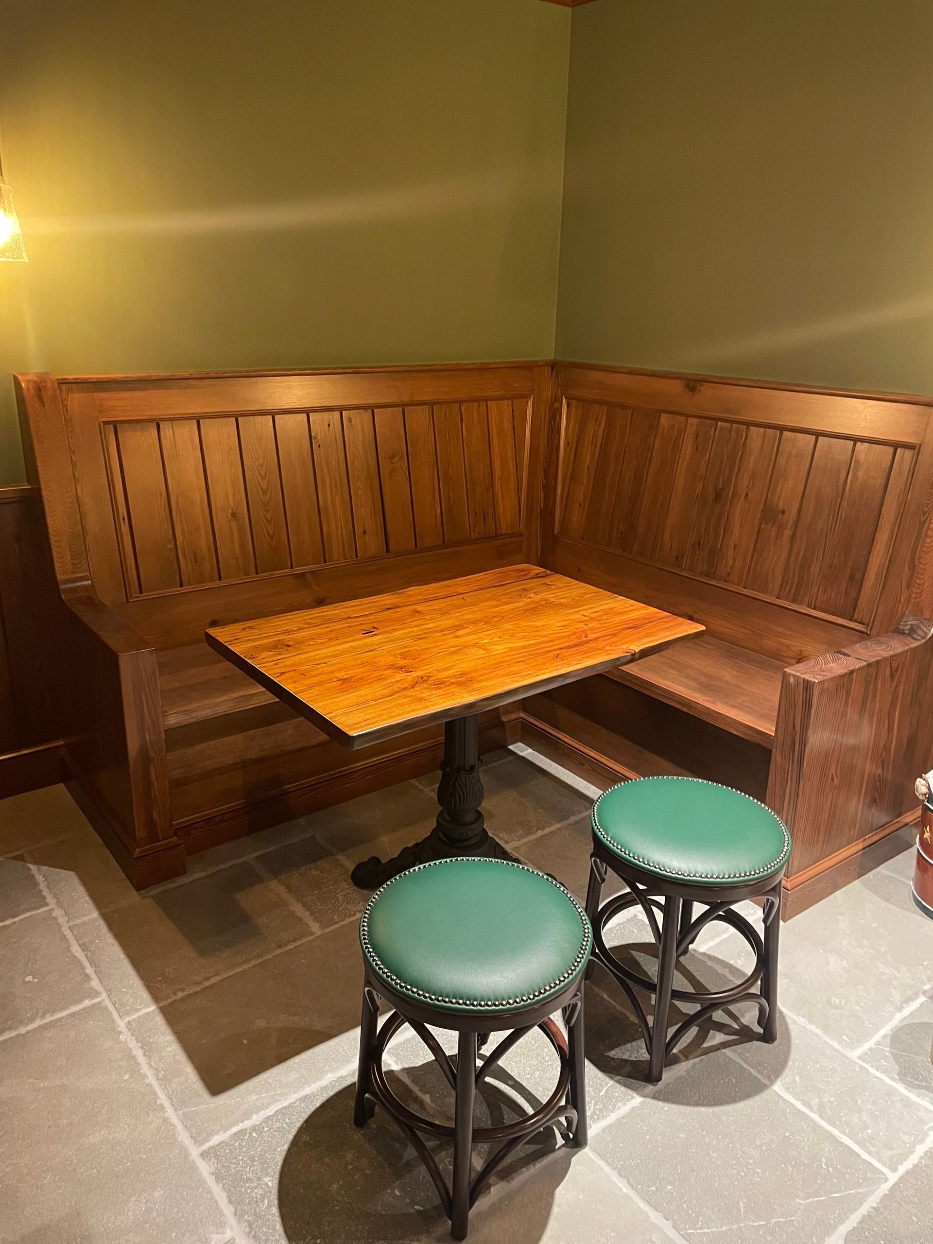 A wooden bench with a table and two stools in a room.