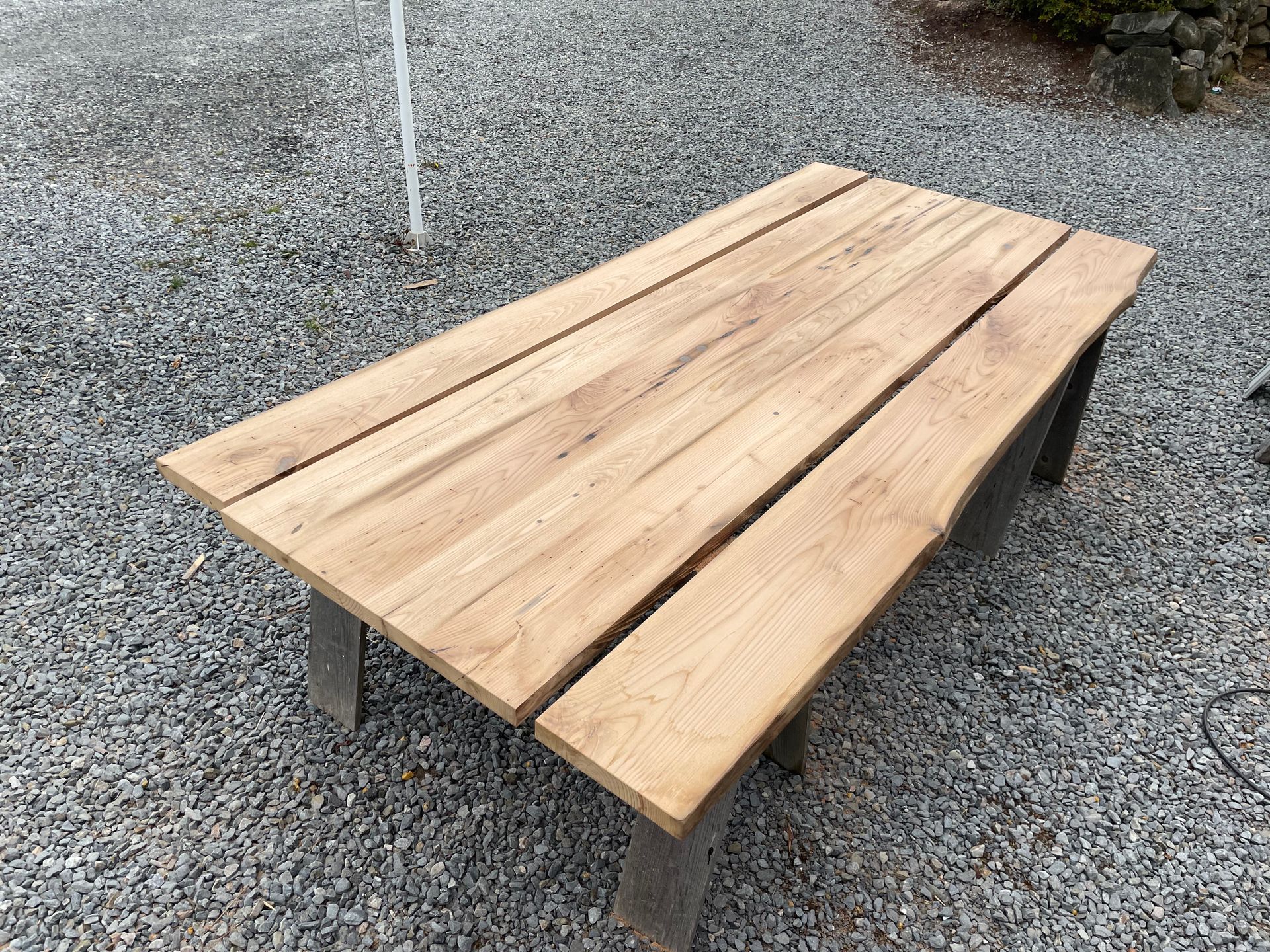 A wooden table with two benches is sitting on gravel.