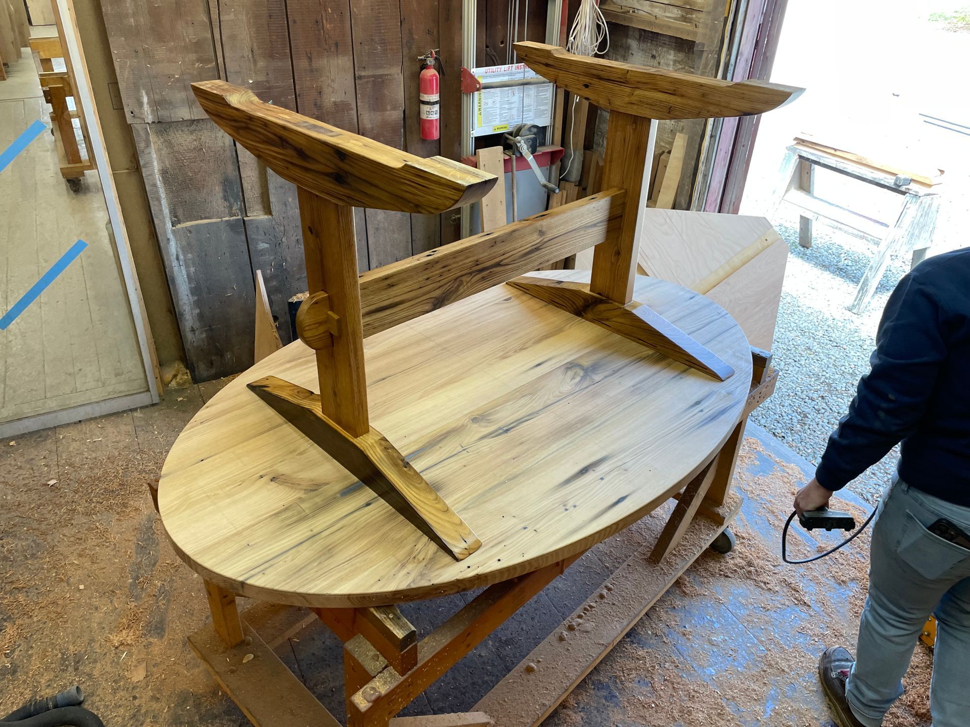 A man is working on a wooden table in a workshop.