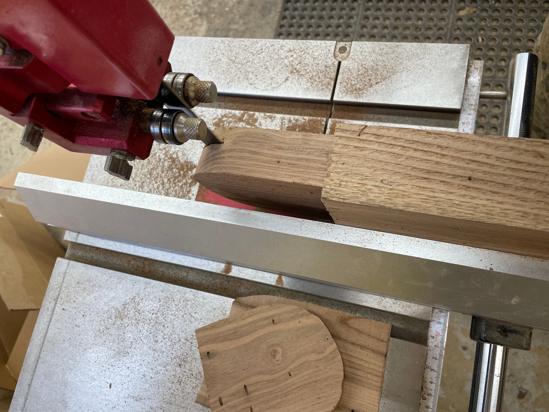 A band saw is cutting a piece of wood on a table.