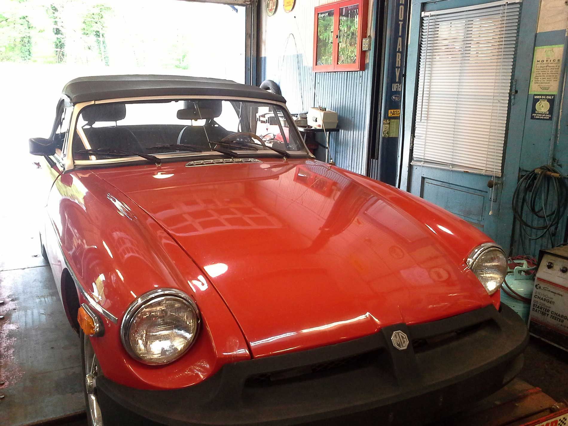 A red sports car is parked in a garage