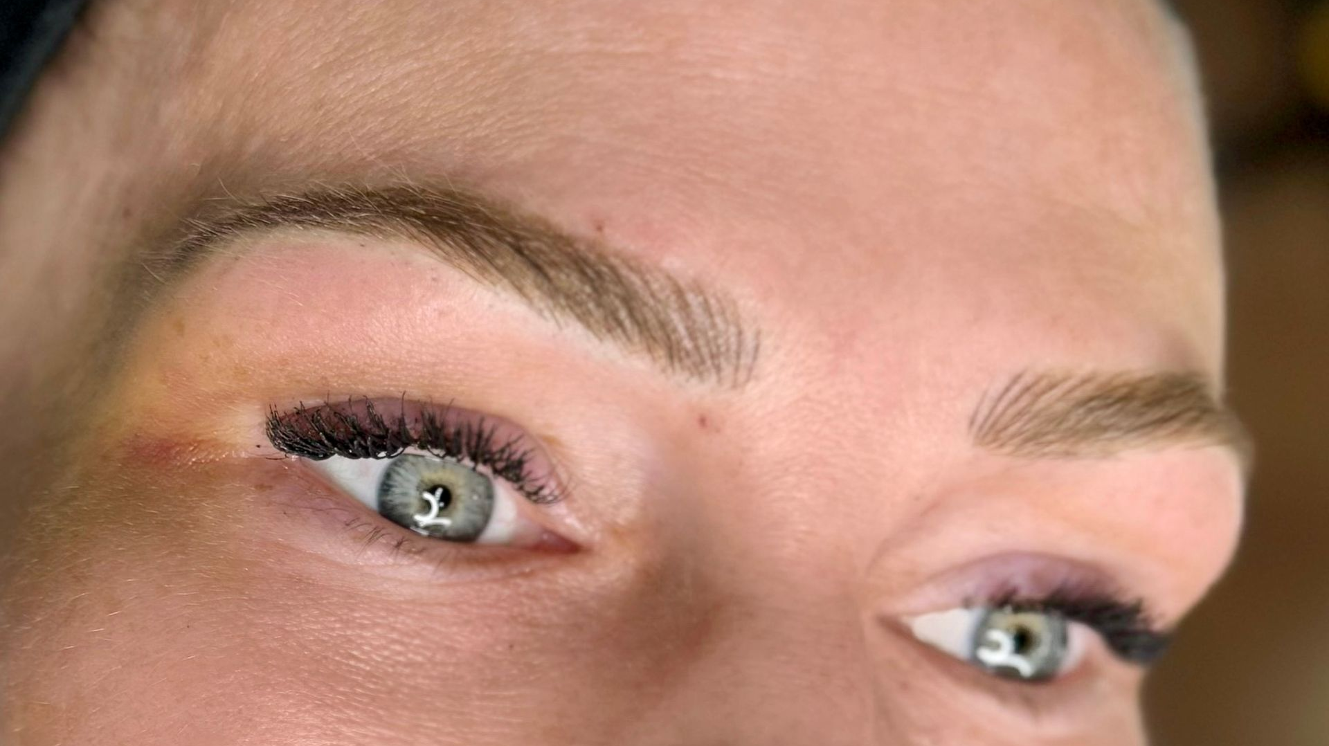 Close-up of person's face with light brown eyebrows, blue eyes, and visible eyelashes.