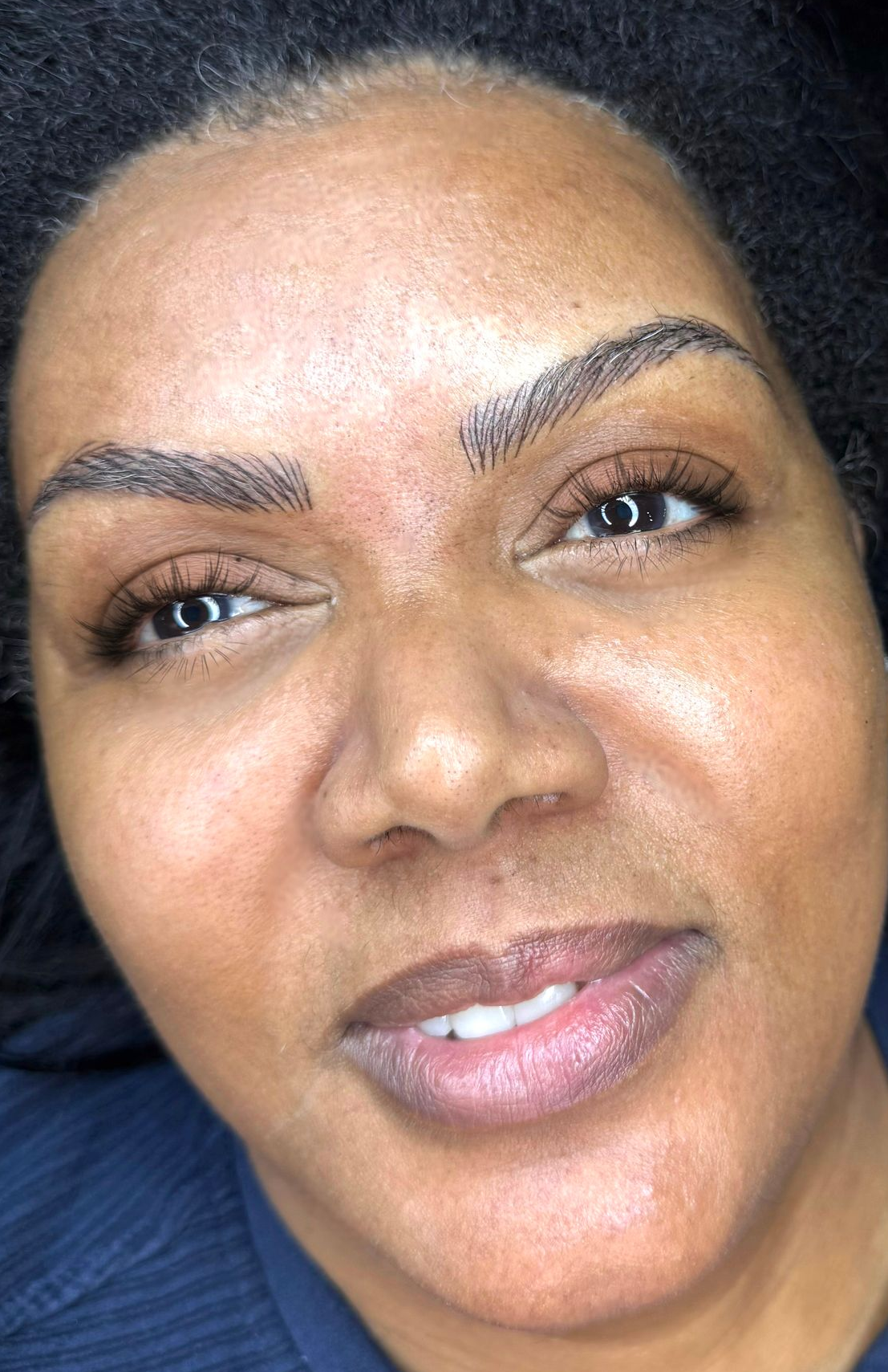 Woman with newly tattooed eyebrows, looking up, lying down.