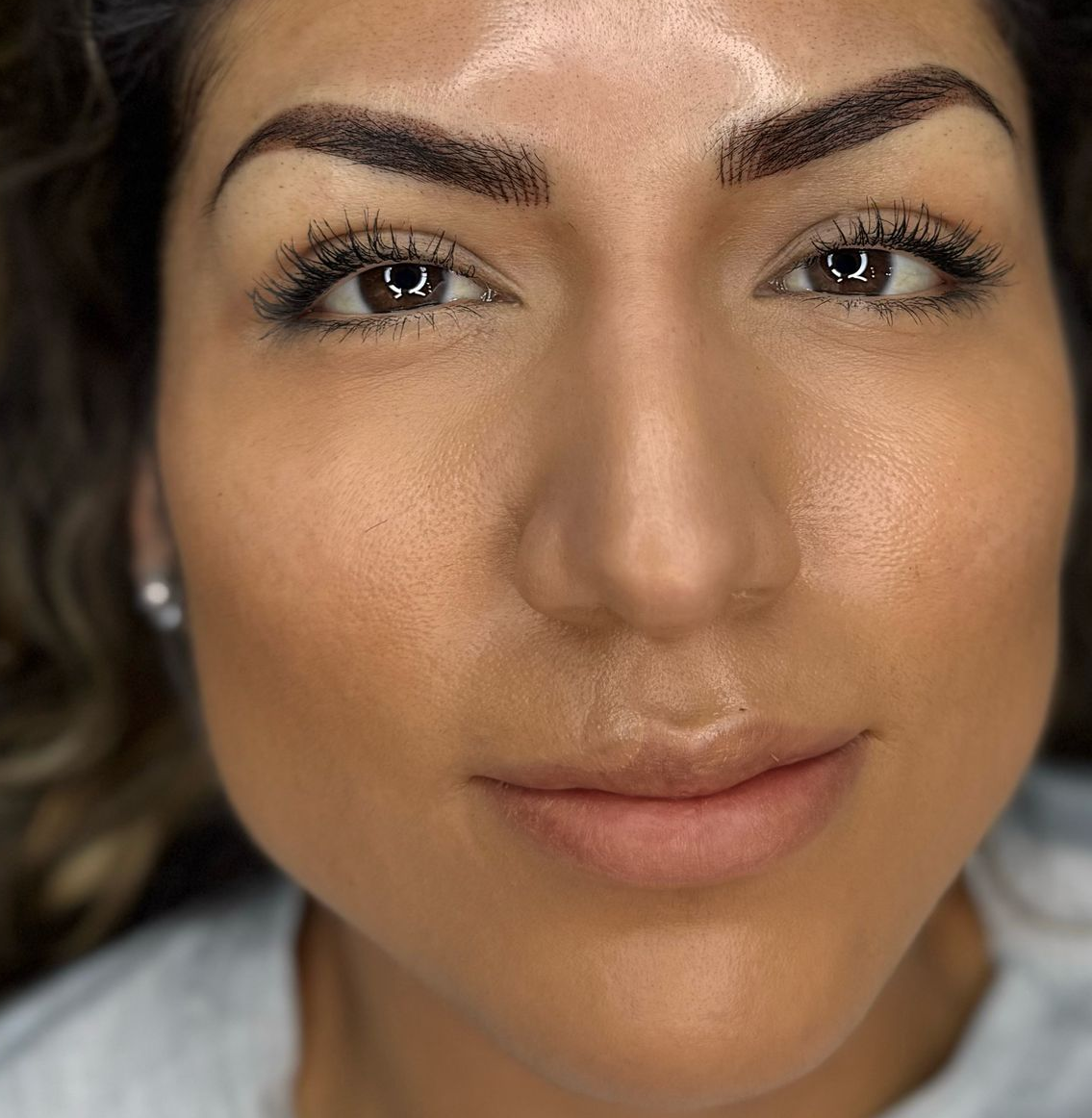 Woman with freshly done eyebrows, close-up, indoors, looking at the camera.
