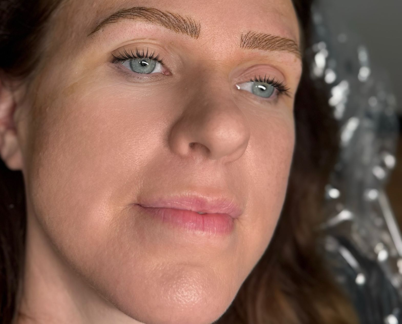 Woman with microbladed eyebrows; light brown pigment on brows, fair skin, light eyes.