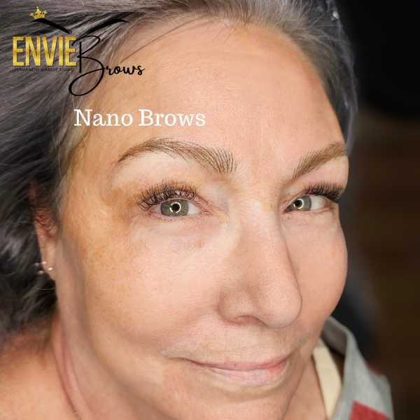 Close-up of a person with professionally done eyebrows. Text reads "Envie Brows Nano Brows".