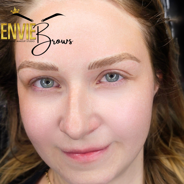 Woman with light brown eyebrows, light skin, and blue eyes. Smiling with a soft glow.