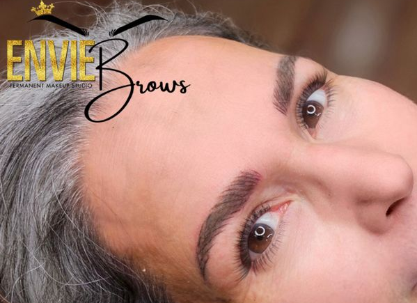 Woman with newly tattooed eyebrows; studio setting.