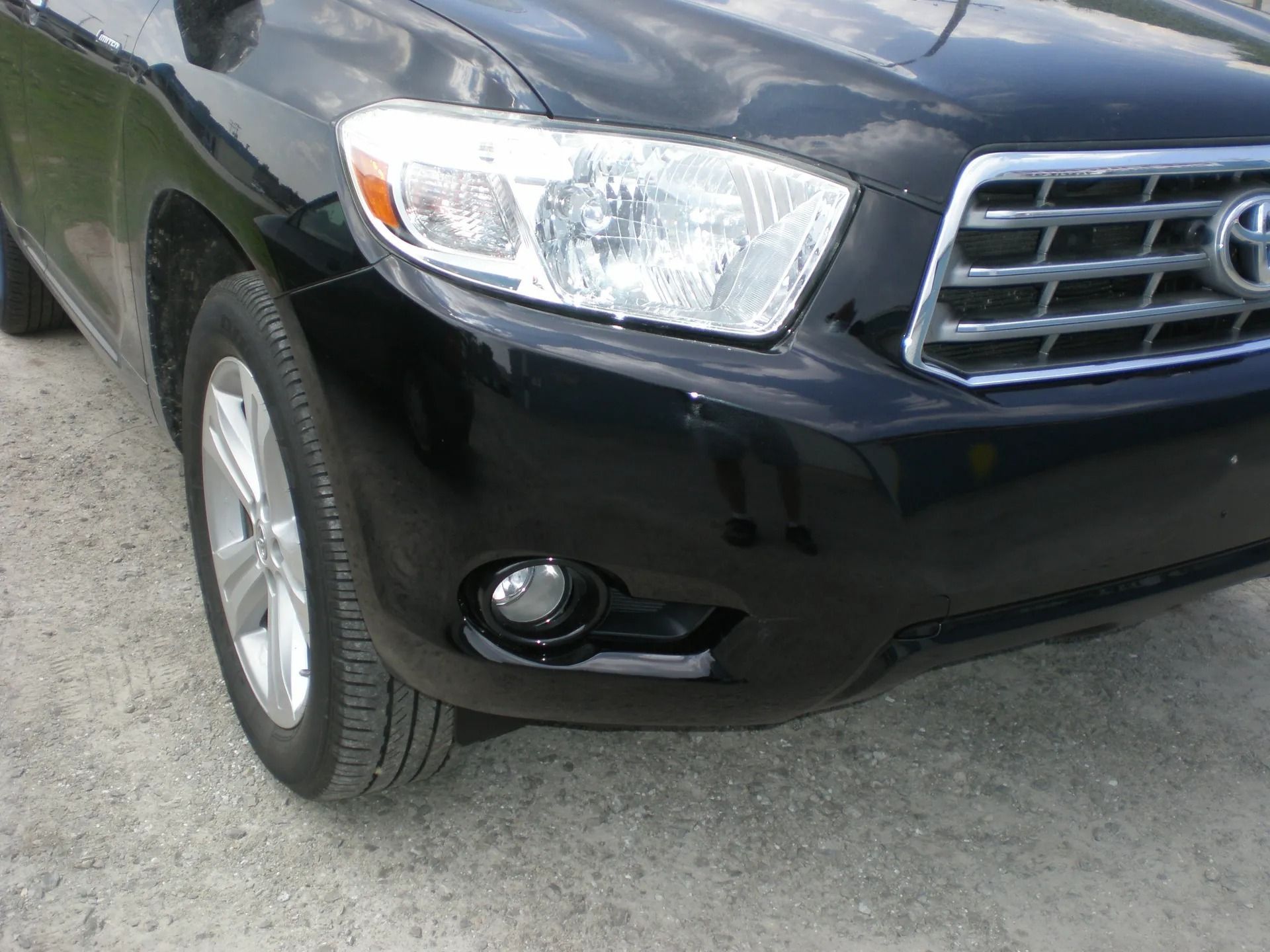 Black Toyota Highlander SUV, front view, parked on gravel.