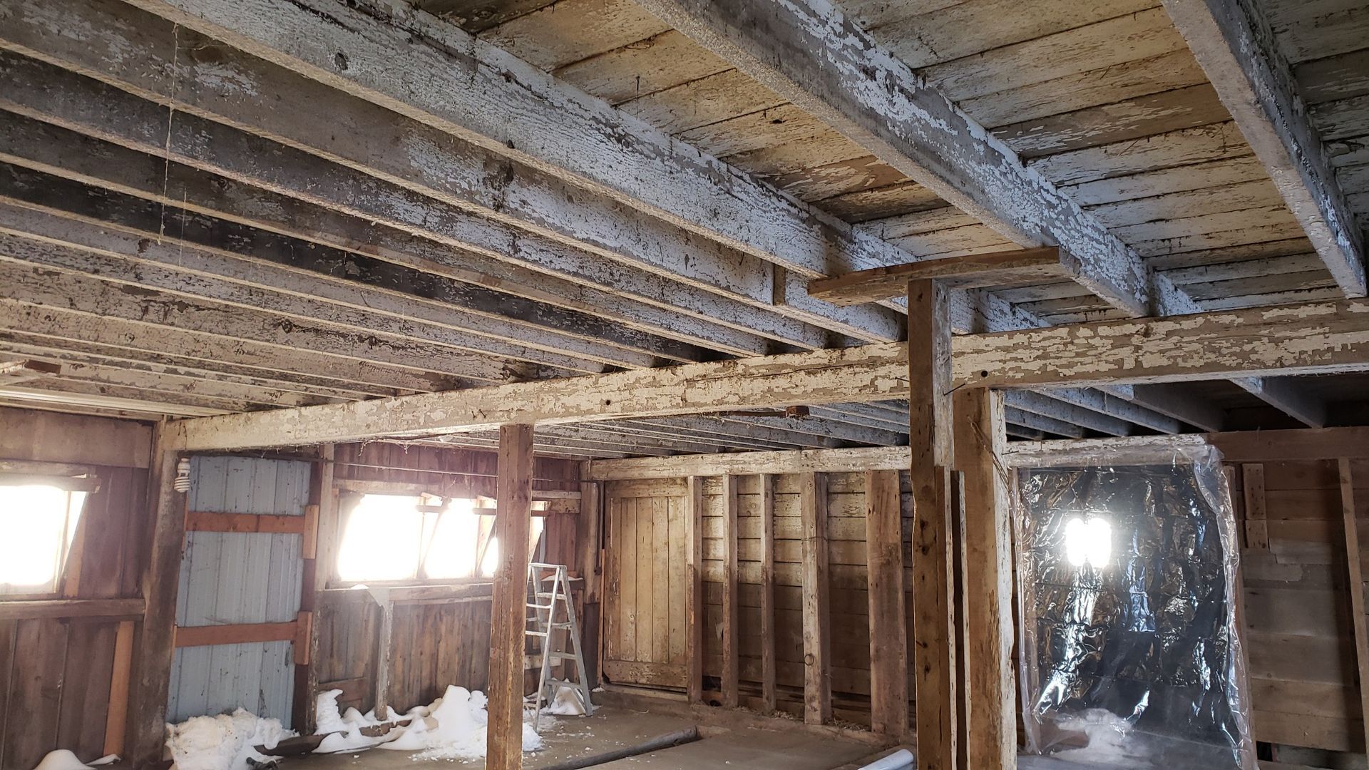 A room with wooden beams and a ladder in it.