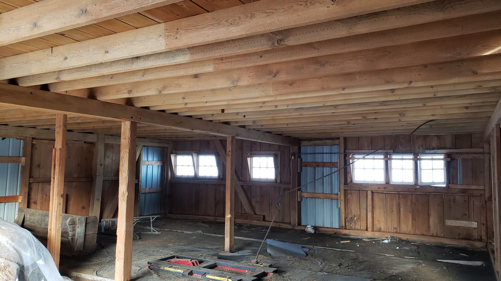 The inside of a wooden barn with a ceiling and a lot of windows.