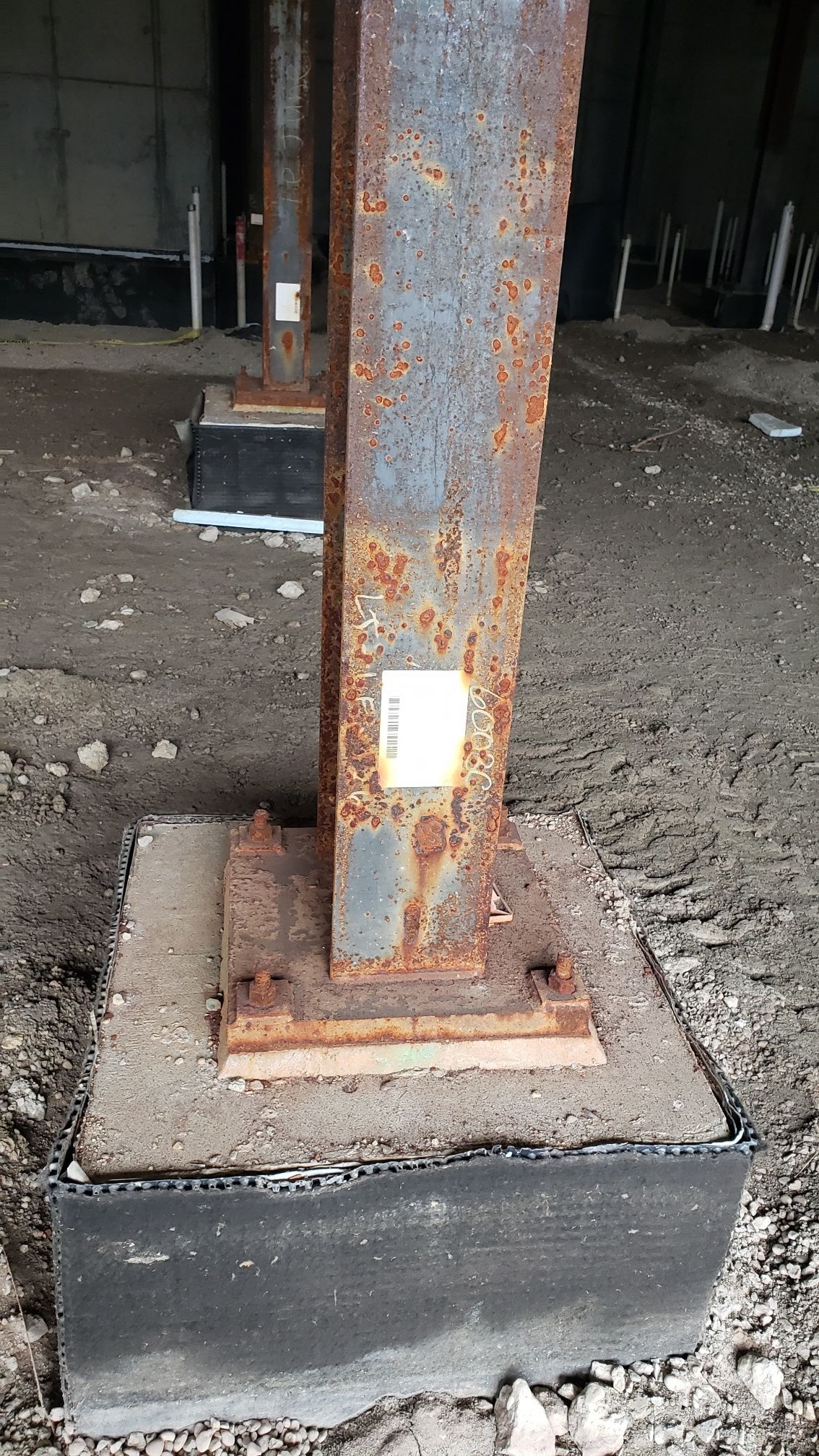 A rusty metal pole is sitting on top of a concrete base.
