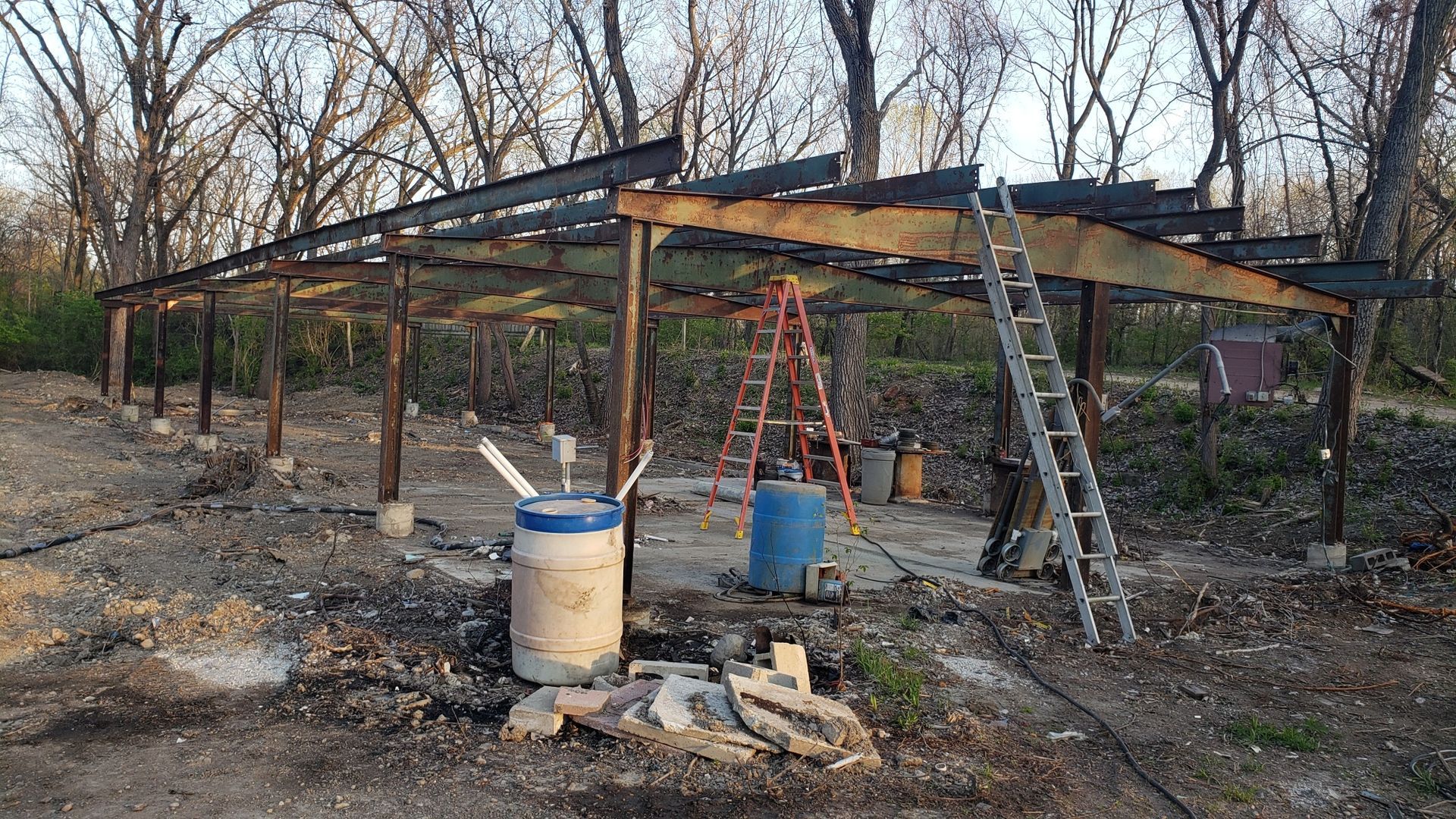 A ladder is sitting under a wooden structure in the middle of a forest.