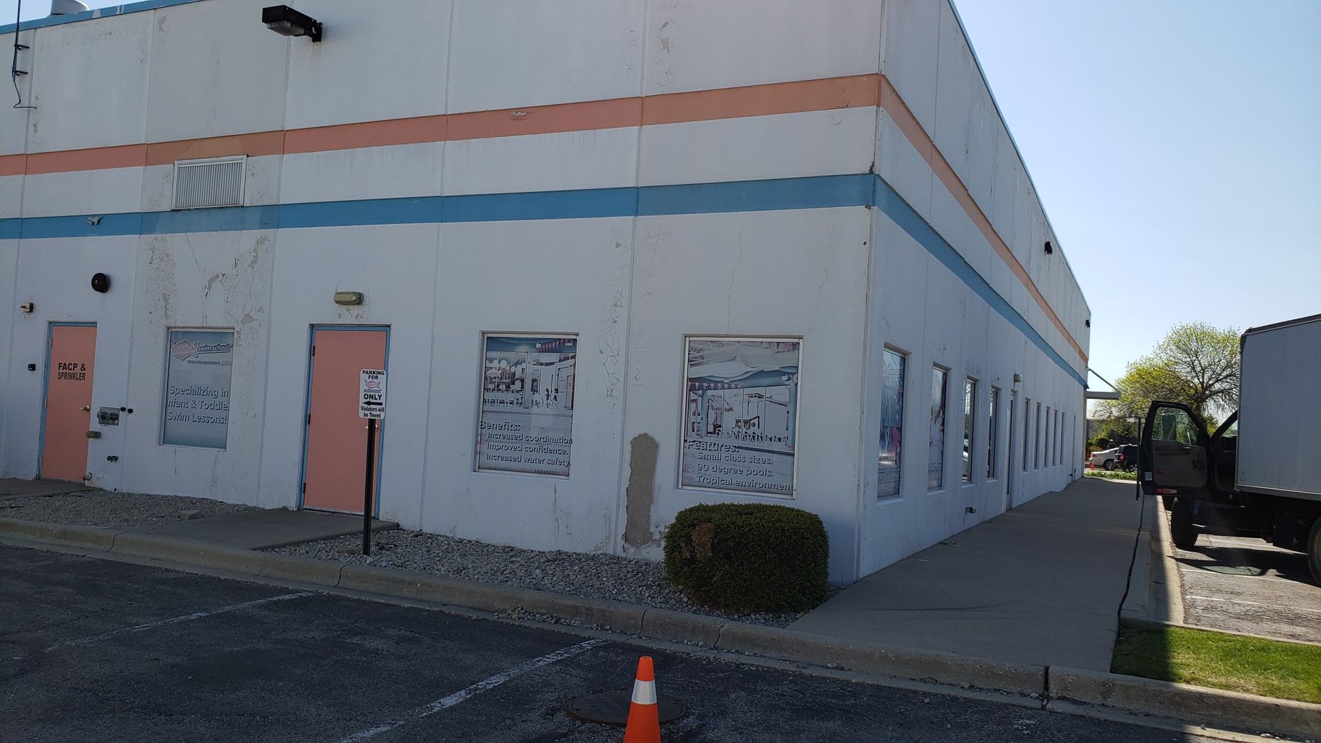A large white building with a lot of windows and a truck parked in front of it.