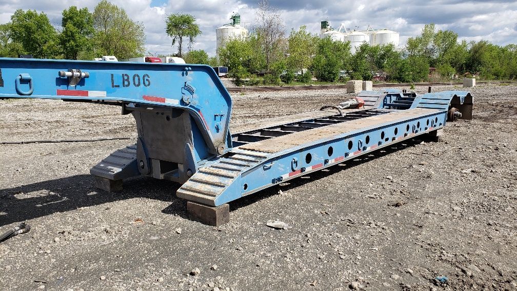 A blue trailer is sitting on top of a dirt field.