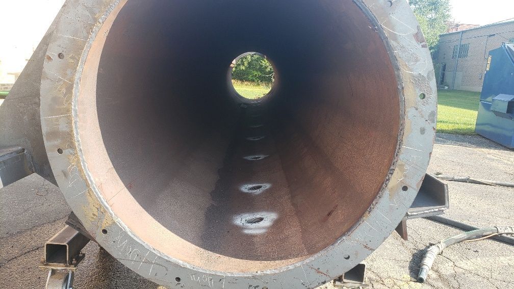 A large metal pipe with a hole in the middle is sitting on the ground.