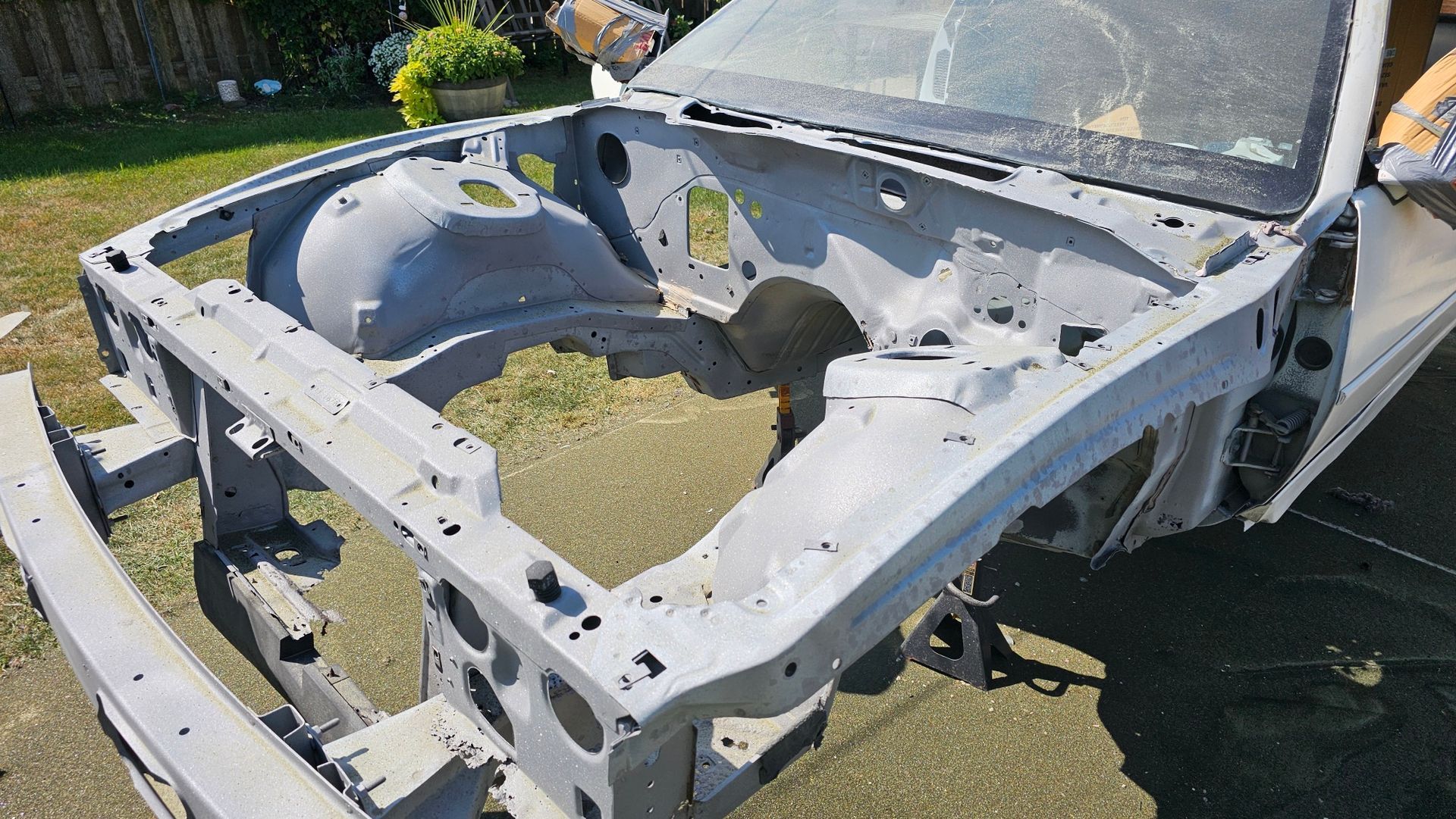 The hood of a car is missing and is sitting on the ground.