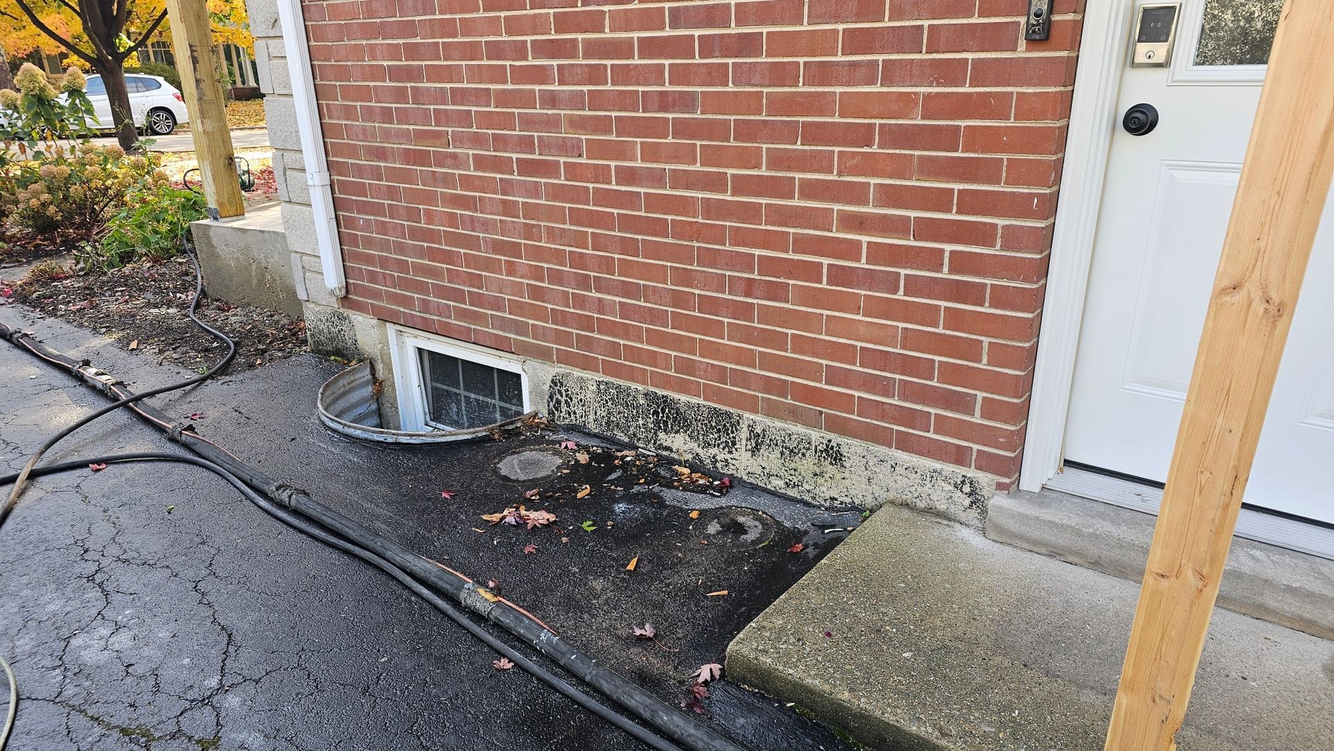 A brick building with a white door is being cleaned with a hose.