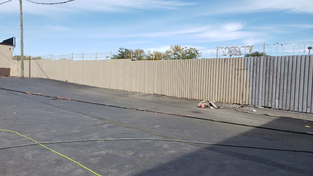A fence is surrounding a parking lot with a yellow line on the ground.