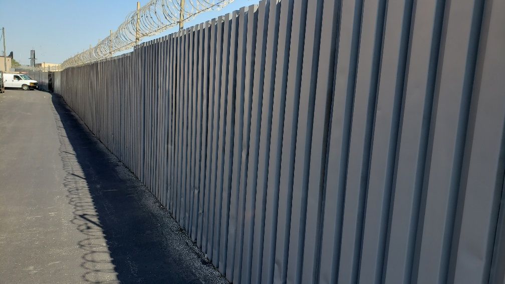 A long fence with barbed wire along the side of the road.