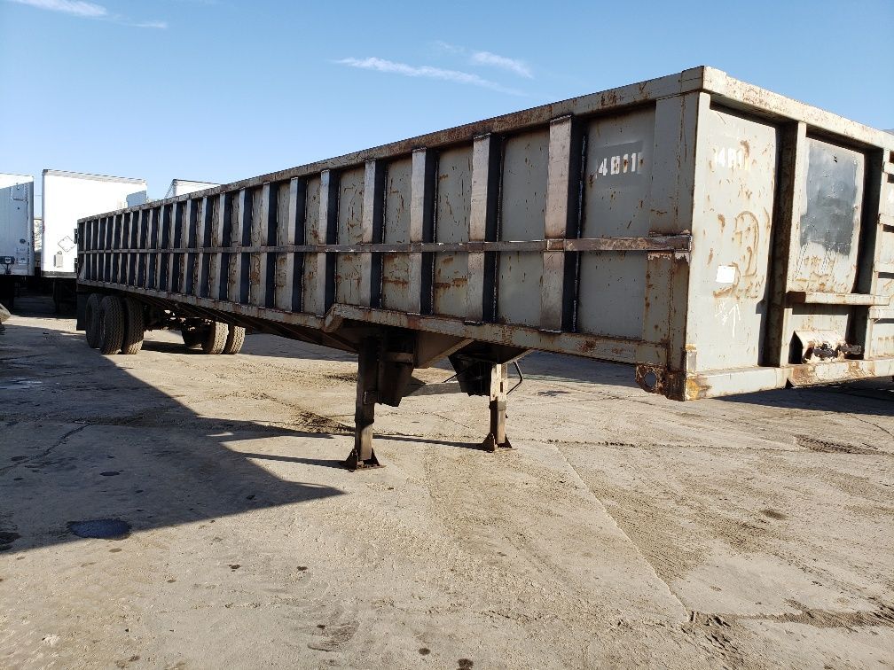 A large dump trailer is parked in a dirt lot.