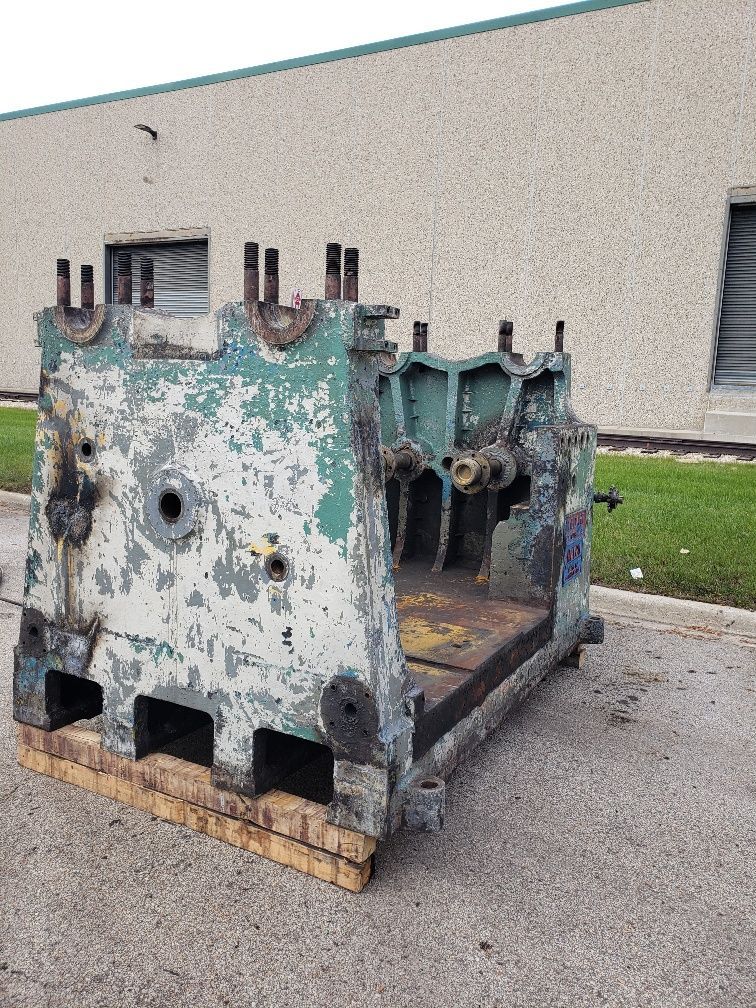 A large piece of metal is sitting on the side of the road in front of a building.