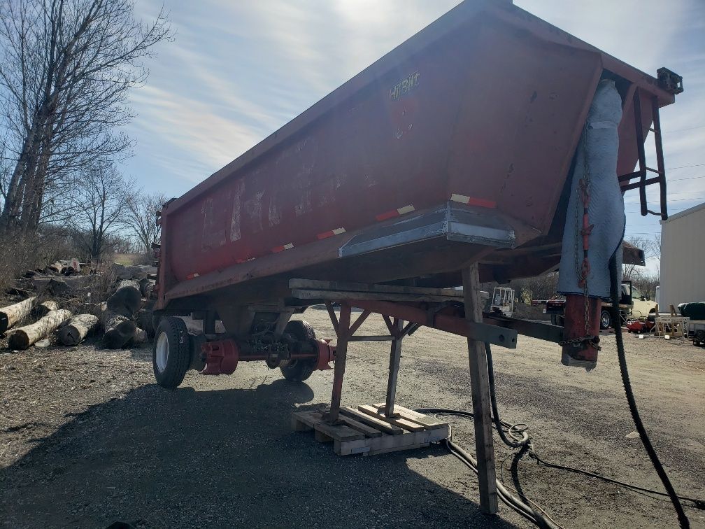 A red dump truck is parked in a gravel lot.