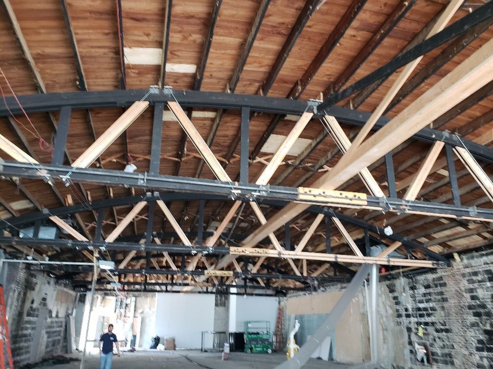 A man is standing under a wooden ceiling in a building under construction.