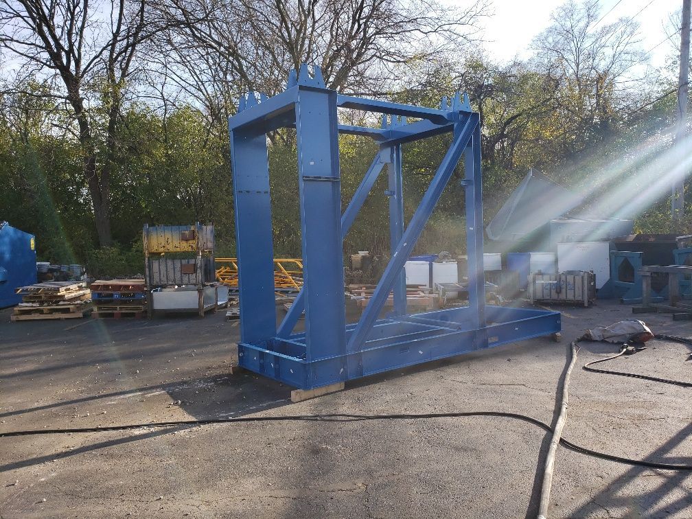 A large blue metal structure is being sprayed with water