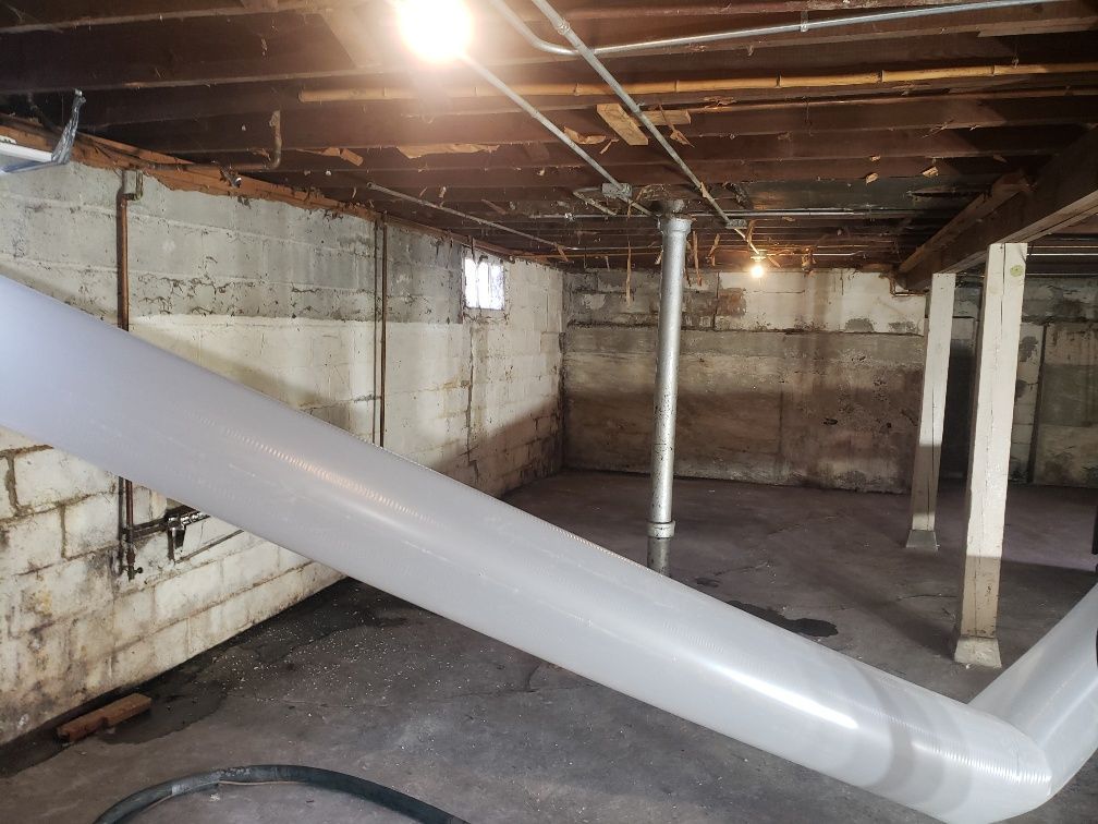 An empty basement with a pipe hanging from the ceiling.