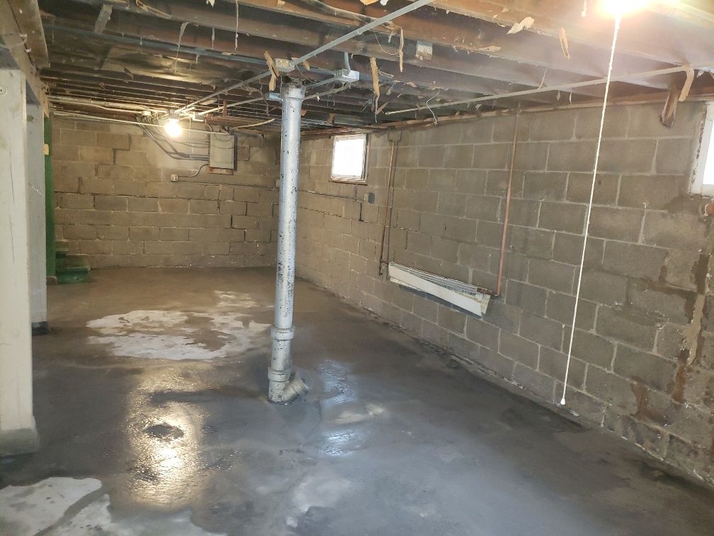 An empty basement with brick walls and a pipe.