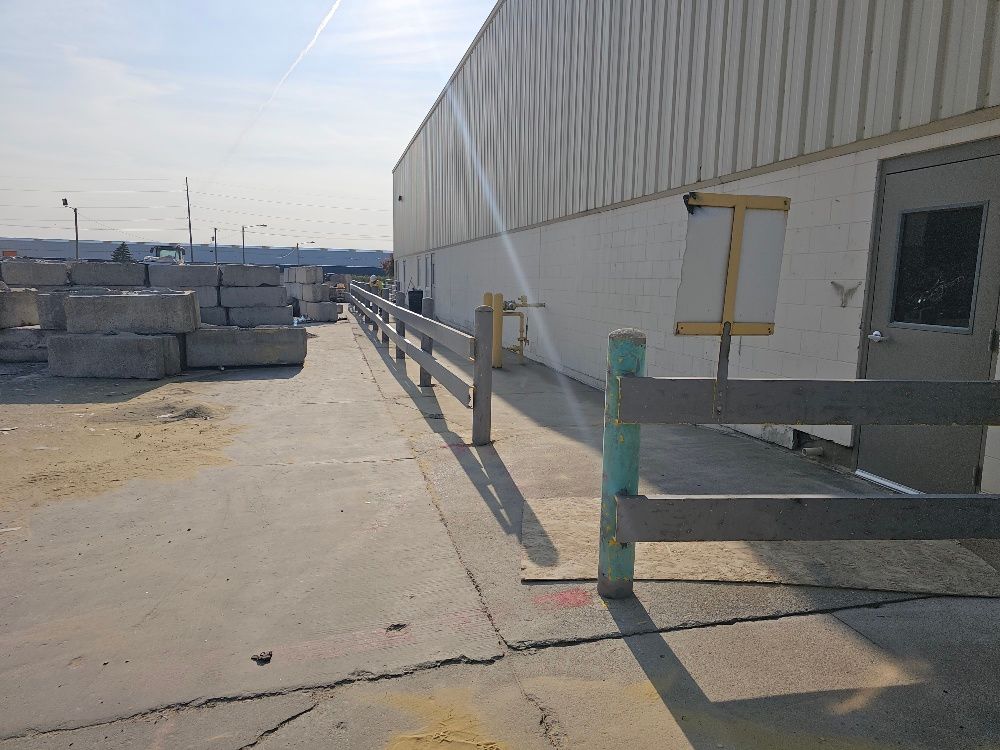 A concrete walkway leading to a building with a wooden fence.