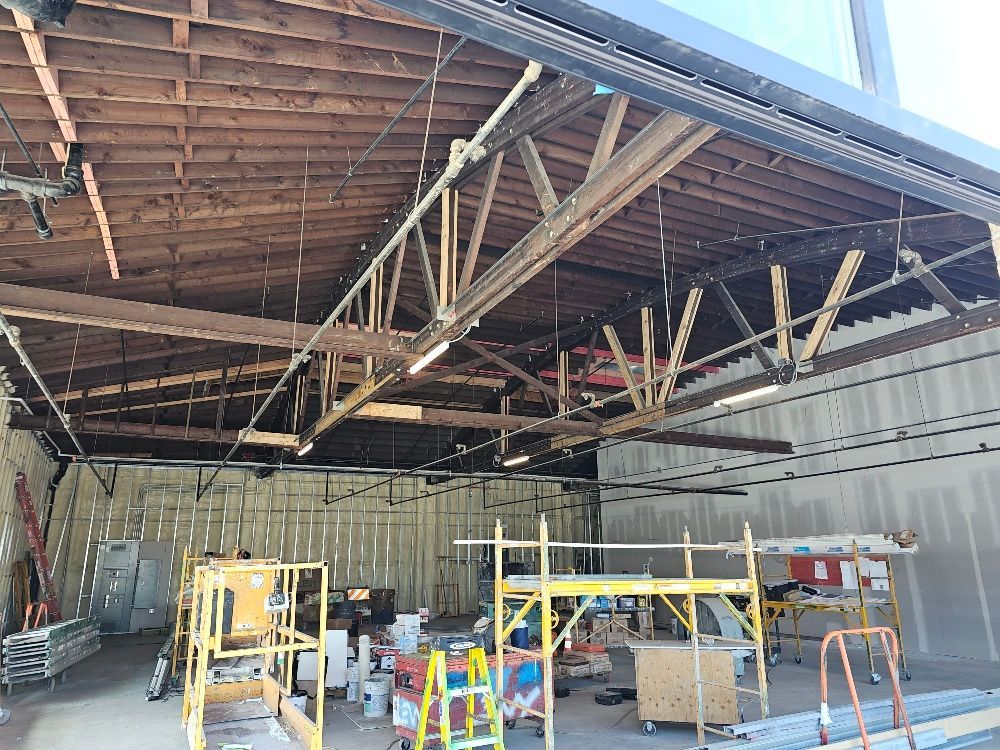 The inside of a building under construction with a lot of wooden beams hanging from the ceiling.