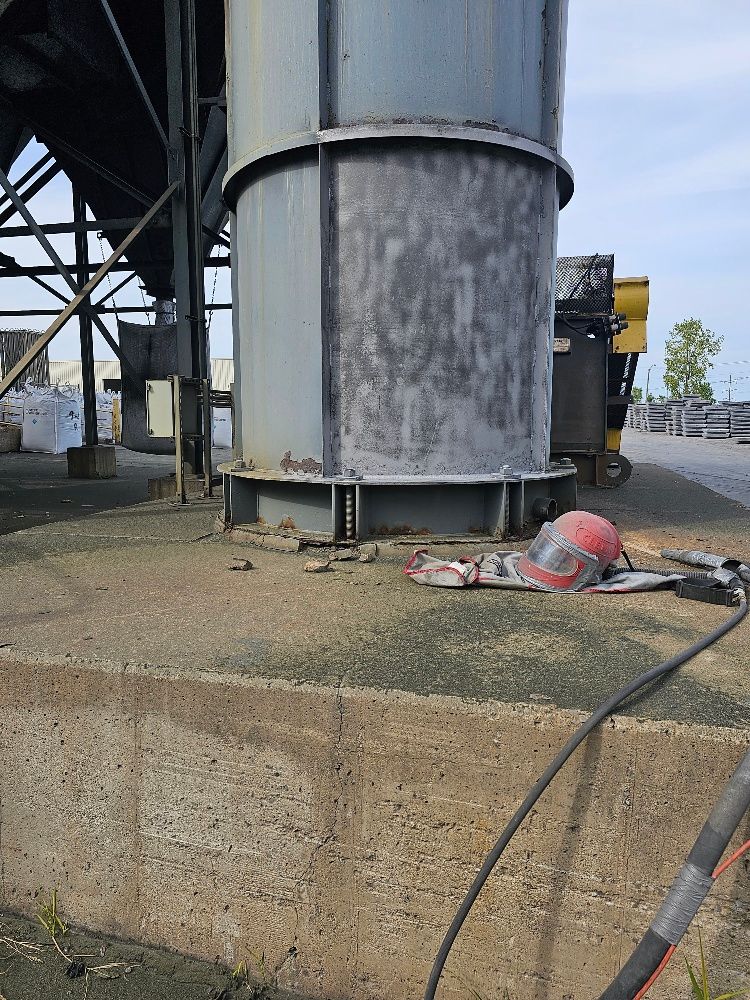 A red hat is laying on the ground next to a large metal structure.