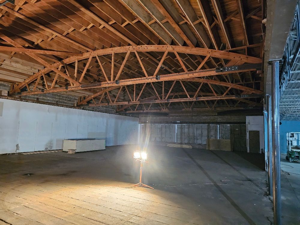 An empty warehouse with wooden beams and a light on the floor.