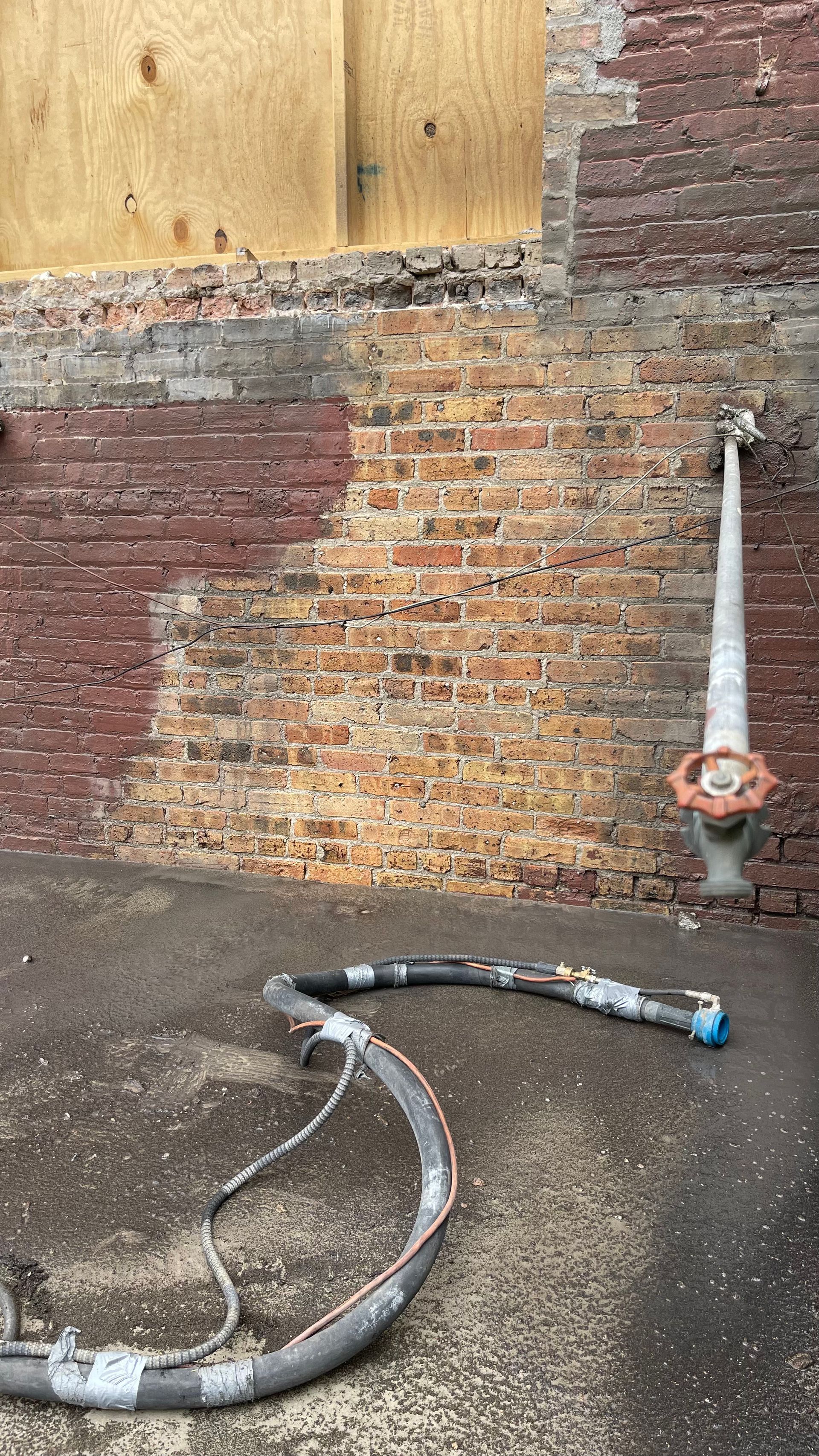 A hose is sitting in front of a brick wall.