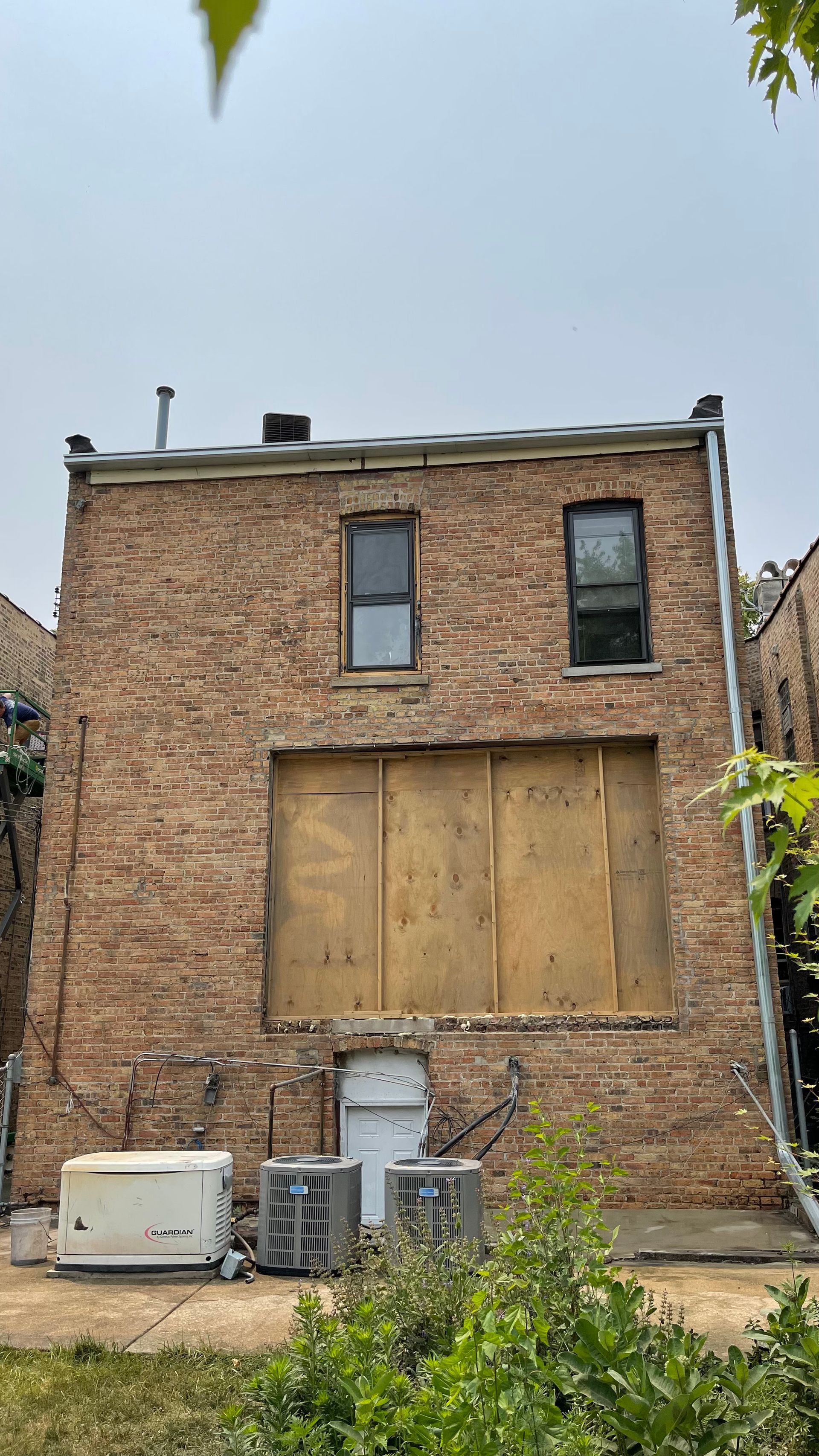 A white truck is parked in front of a building covered in plastic.
