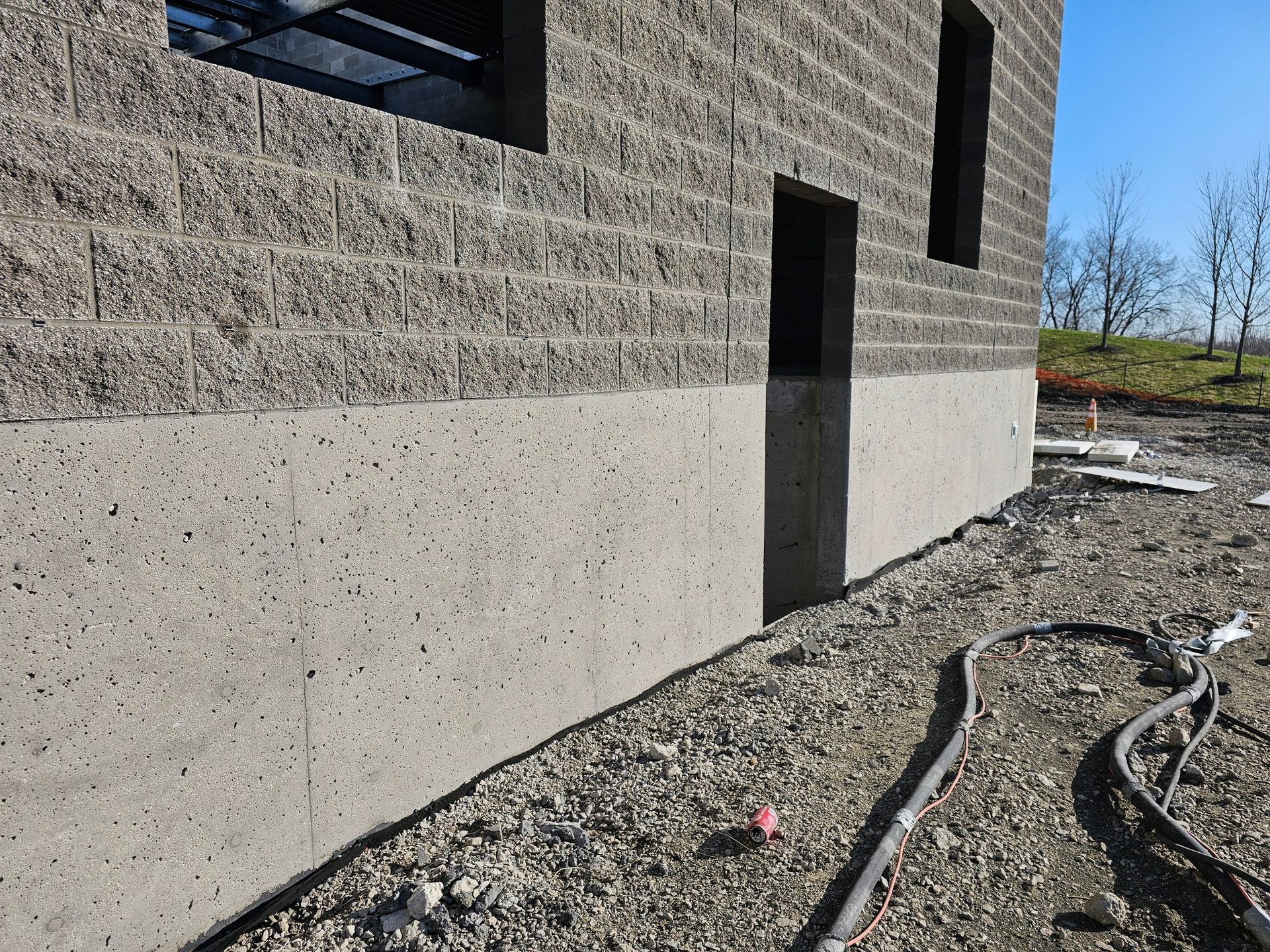 A brick building under construction with a hose on the ground in front of it.