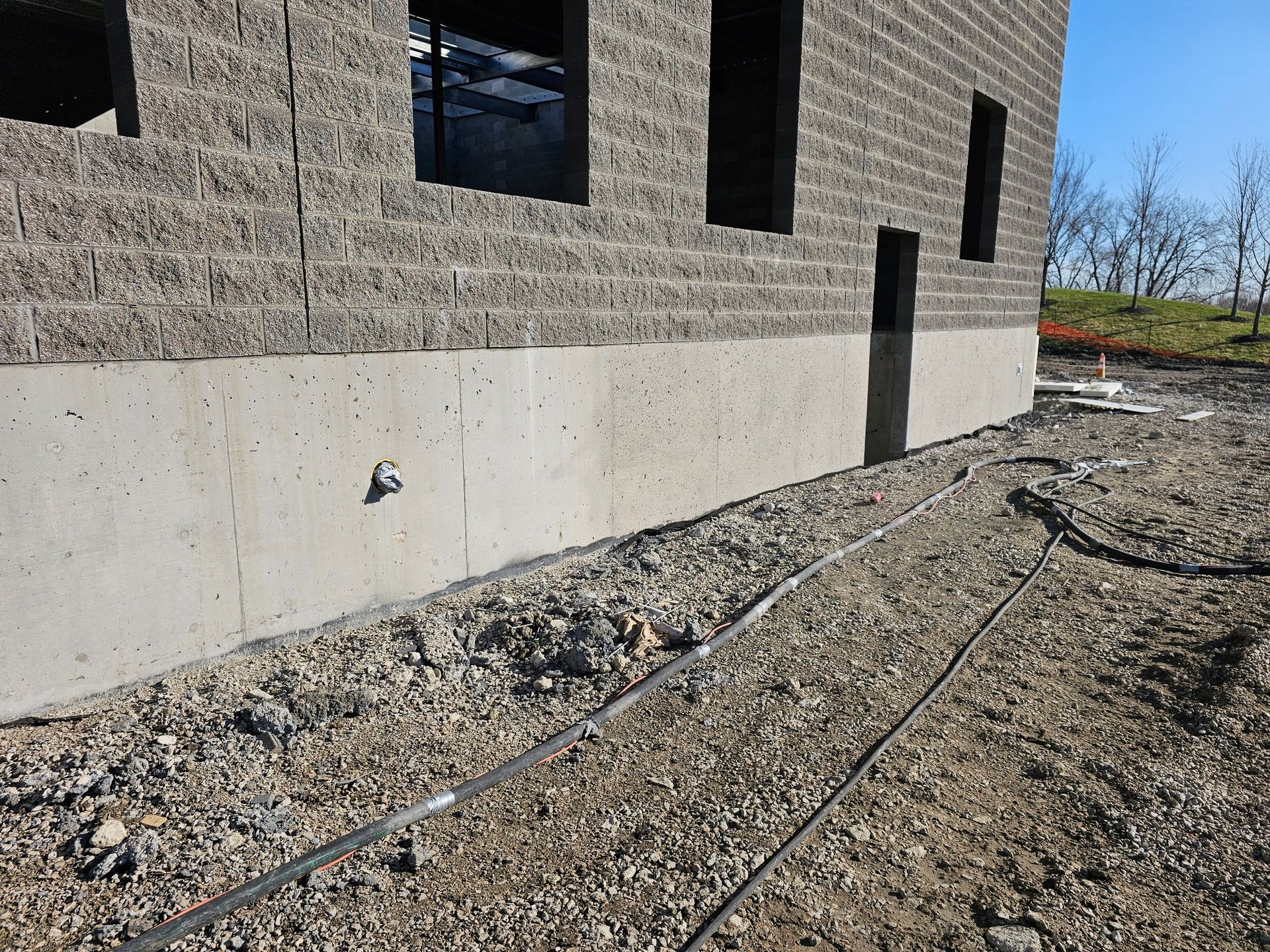 A brick building is being built next to a gravel road.