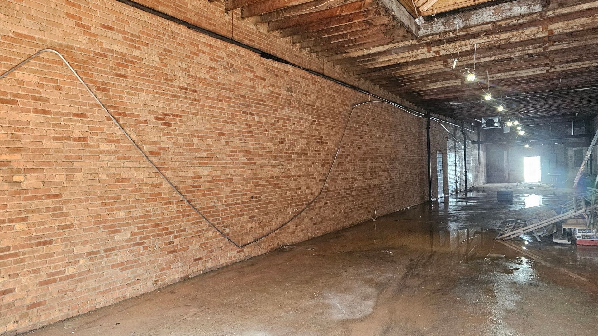 A large empty room with a brick wall and a wooden ceiling.