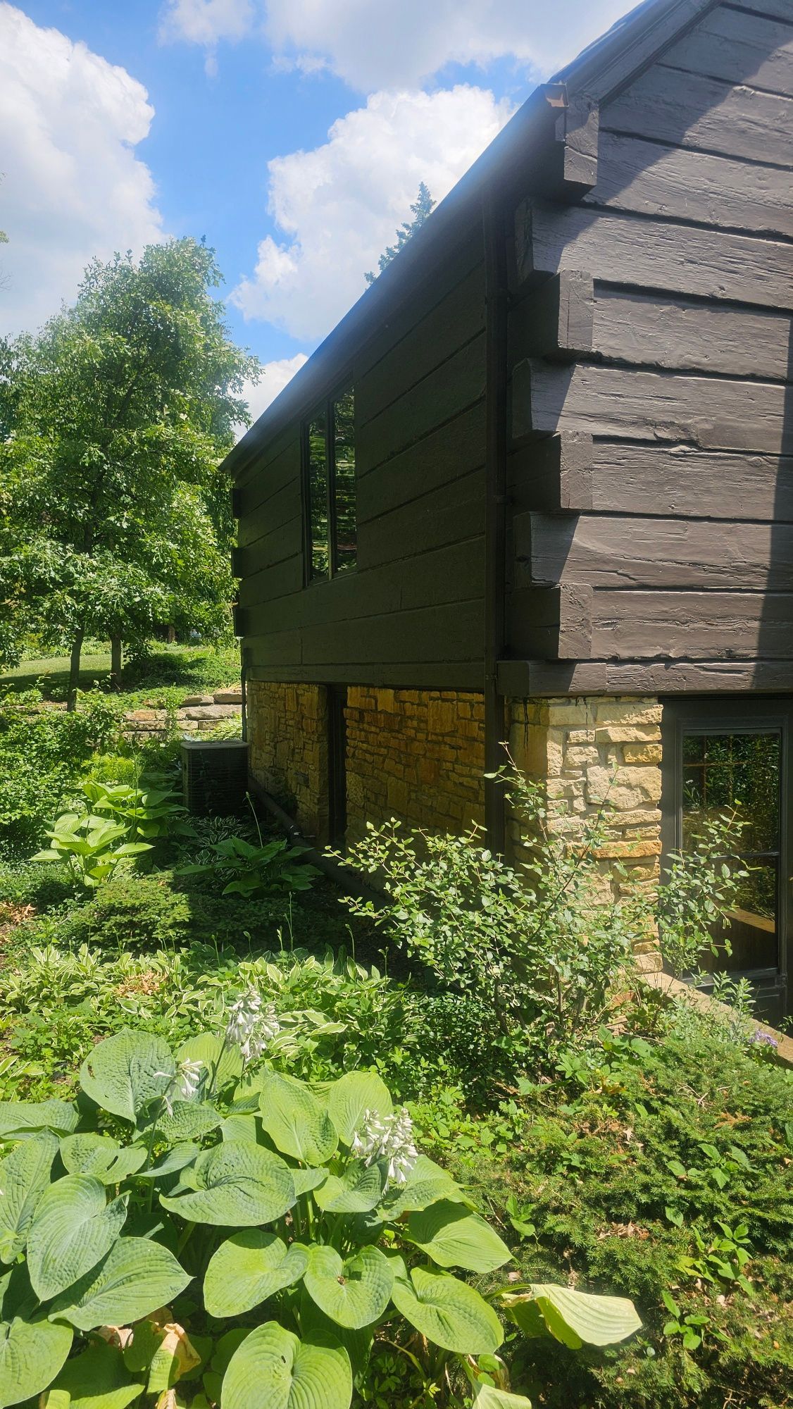 A wooden house with a lot of plants in front of it.