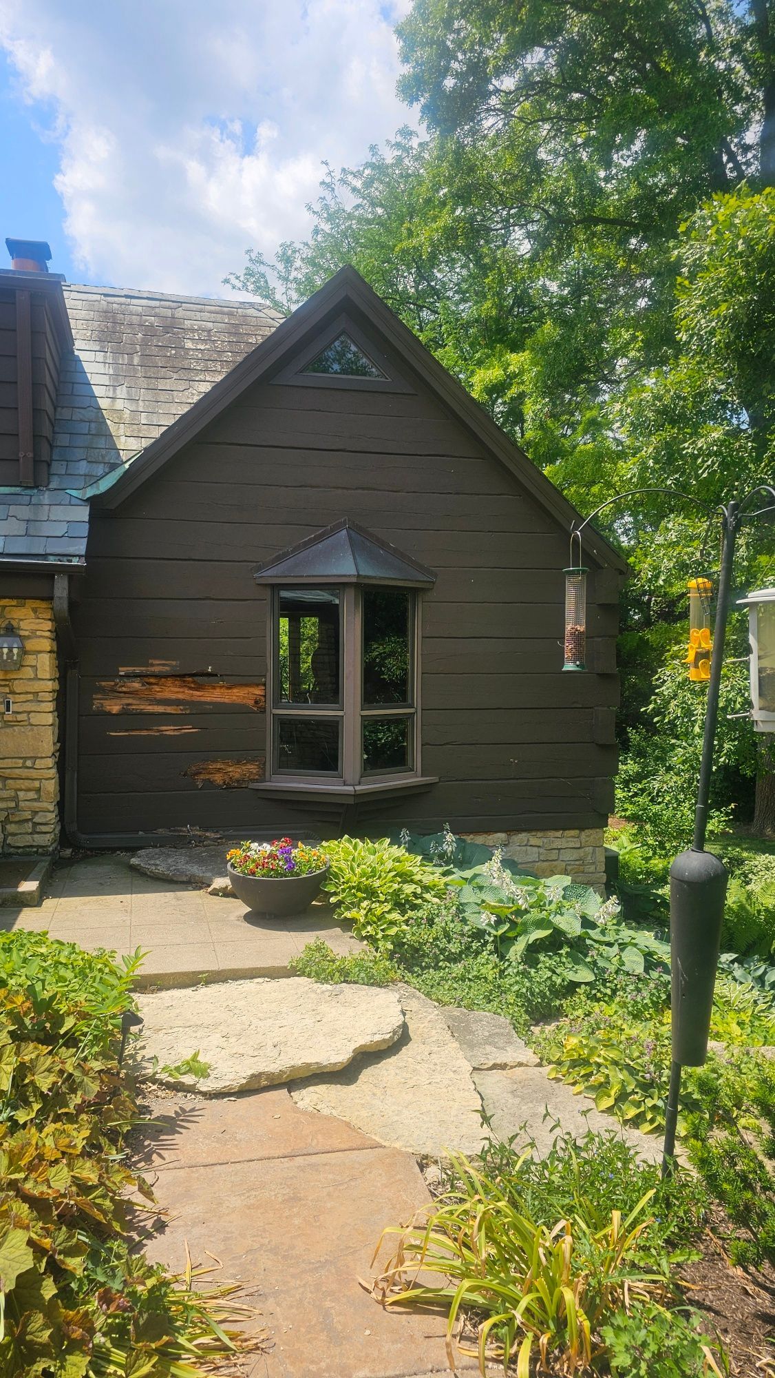 A small house with a bird feeder on the side of it.