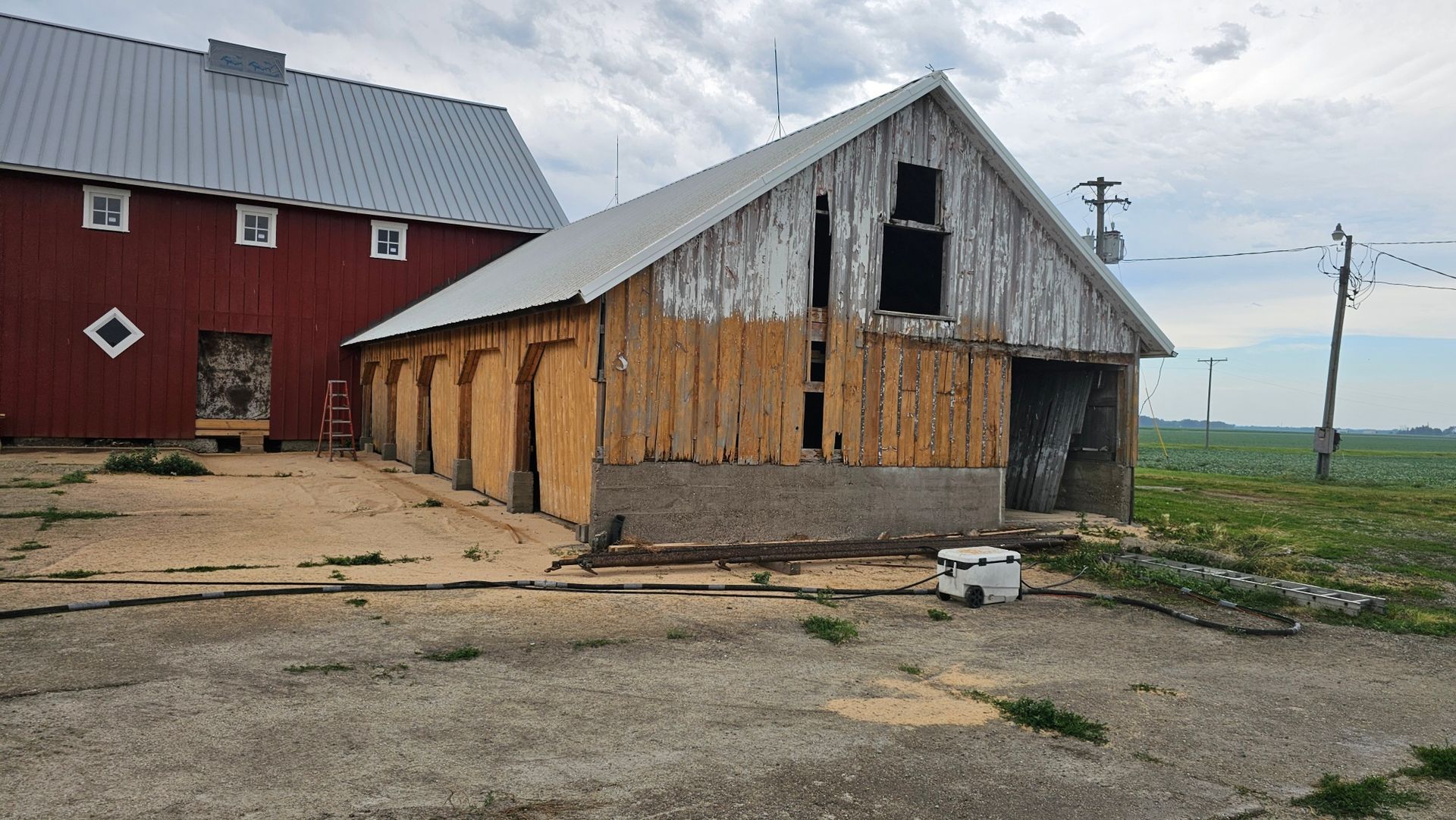 A barn with a red barn in the background is being remodeled.