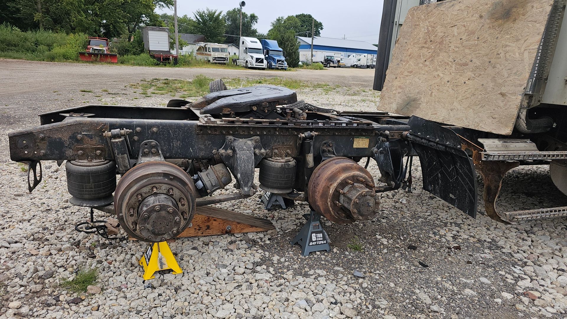 A truck is sitting on a gravel road with a yellow a on the ground