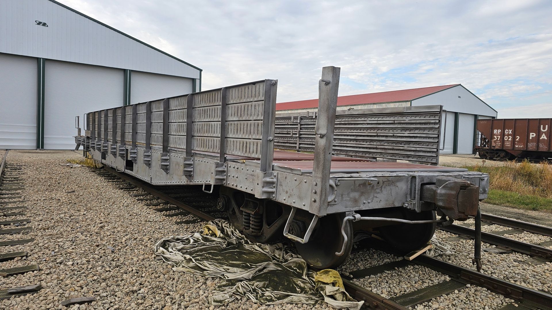 A train car is sitting on the tracks in front of a building