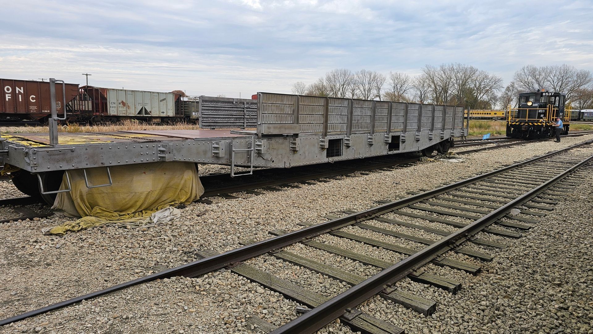 A train car is sitting on the tracks next to another train car.