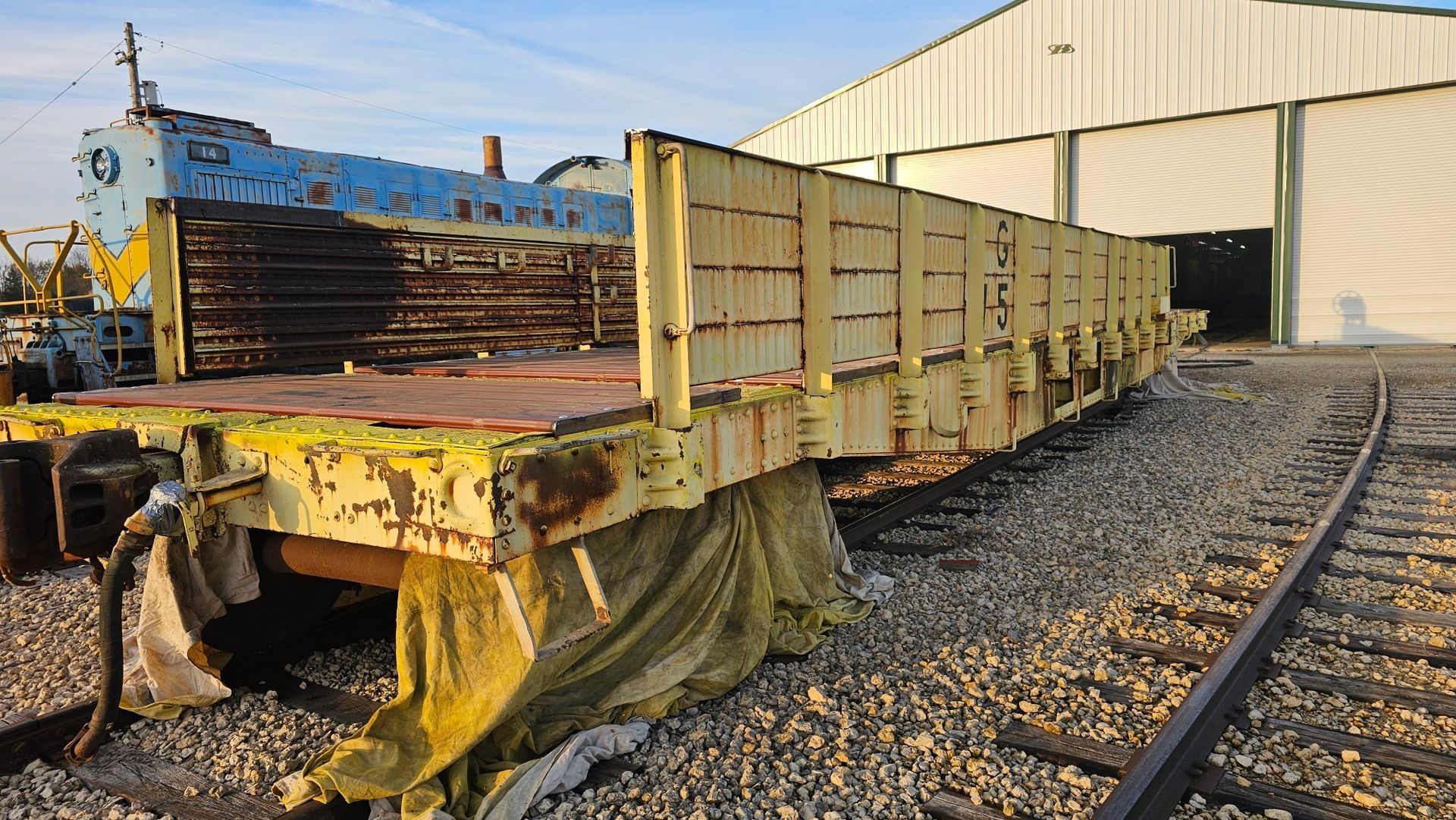A train car is sitting on the tracks in front of a building