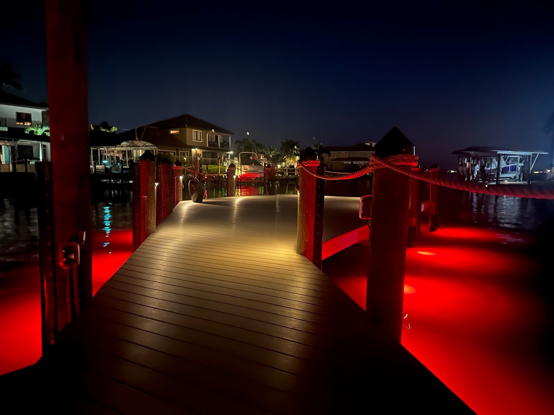 A dock with red lights on it is lit up at night.
