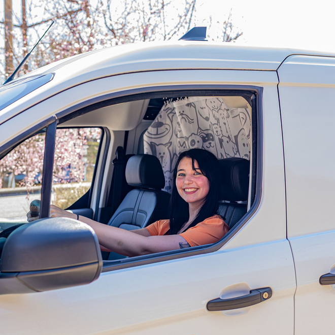 Woman smiling in the driver's seat of a white van with business logo "Mals Pals Pet Dental Cleaning" and phone number.